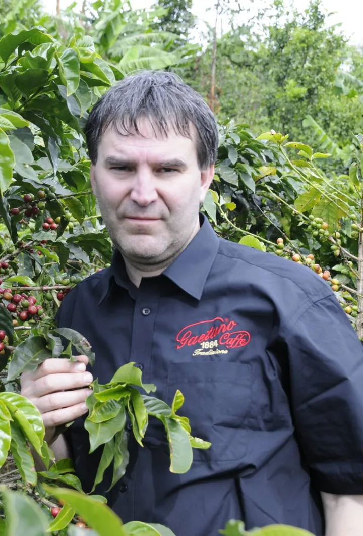 Jiří Sýkora u kávovníku se zralými červenými plody na plantáži